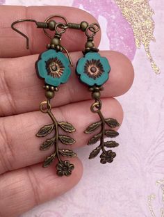 Flowers, flowers, and more flowers! The beautiful teal flowers are Czech glass beads. I paired them with high quality Vintaj charms, which are solid brass and American made using an eco friendly process. The effect of combining natural brass and Czech glass beads is so pretty to me. I love the elegant, vintage look it creates. The hooks on these earrings are antique brass and are nickel free. All of my earrings come on a hand stamped earring card and are lovingly wrapped in colorful tissue and p Vintage Flower Charm Dangle Earrings, Vintage Turquoise Flower Earrings, Brass Flower Charm Earrings, Nickel-free Czech Glass Flower Earrings, Nickel-free Brass Flower-shaped Earrings, Unique Flower Charm Dangle Earrings, Unique Dangle Flower Charm Earrings, Vintage Turquoise Dangle Flower Earrings, Turquoise Flower-shaped Earrings With Flower Charm