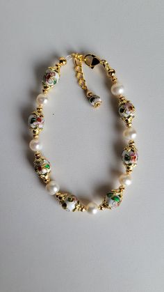 This bracelet is made of round white Cloisonné' beads, white Freshwater pearls and gold plated beads and findings. It has a 1" extension with a beaded drop making it adjustable. It has a lobster claw clasp.  Cloisonné is the technique of creating designs on metal vessels (cloisons) with colored-glass paste placed within enclosures made of copper or bronze wires, which have been bent or hammered into the desired pattern.  Custom Orders are always welcome! Ask about free sizing. White Pearl Beaded Bracelets With 8mm Beads, White Pearl Bracelet With Spacer Beads, White Beaded Pearl Bracelet With Round Beads, White Round Beaded Pearl Bracelet, Adjustable White Pearl Rosary Bracelet, White Beaded Pearl Bracelet, Elegant White Pearl Bracelet With Colorful Beads, White Gold Beads Bracelet, White Pearl Beaded Round Bracelets