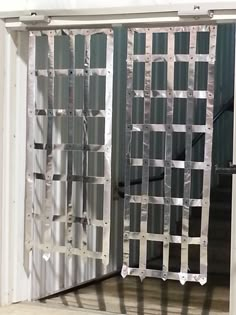 an open sliding door with metal bars on it's sides in front of a white wall