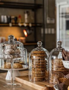 some cookies and pastries under glass on a wooden table with other desserts in the background