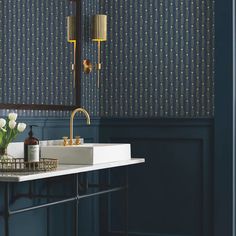 a bathroom with blue walls and wallpaper, gold faucets on the sink