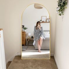 a woman taking a selfie in front of a large mirror with her legs crossed