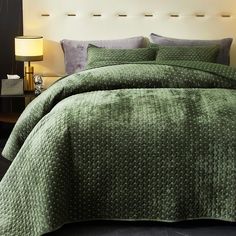 a bed with green bedspread and pillows