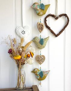 a vase filled with flowers sitting on top of a wooden table next to a heart shaped wall decoration