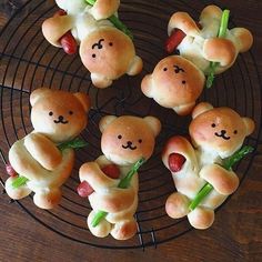 small teddy bears made out of bread sitting on a wire rack with green leaves around them