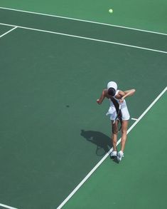 a woman is playing tennis on a green court with her racket in the air