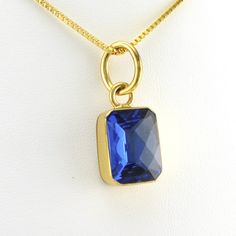 This lab created tanzanite rectangle gemstone is set in alchemía. Gem has a sparkly checkerboard cut. Pendant is 1 3/16 inches long and 1/2 inch wide and is sold separate from the 18k gold fill 1.2mm box chain shown. Alchemía a blend of base metals that looks like 18k gold and will not change color and is hypoallergenic. Style Number: 19209 Metal: Alchemía Gemstone: Lab Created Tanzanite Dimensions: 1 3/16 inches long and 1/2 inch wide Handmade in Mexico Sapphire Jewelry With Rectangular Stone For Gift, Faceted Rectangular Jewelry As A Gift, Rectangular Tanzanite Jewelry For Anniversary, Rectangular Faceted Yellow Gold Jewelry, Gold Faceted Jewelry With Rectangular Stone, Gold Rectangular Faceted Necklace, Gold Faceted Rectangular Necklace, Elegant Rectangular Pendant Gemstone Jewelry, Gold Faceted Rectangular Stone Jewelry