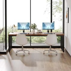 two computer monitors sitting on top of a wooden desk in front of a large window