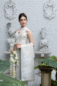 a woman standing in front of a white brick wall wearing a dress and holding a tassel