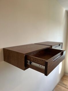 a wooden shelf with a drawer on it's side hanging from the wall in an empty room