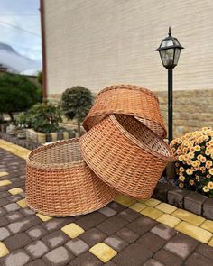 two wicker baskets sitting on the ground next to a lamp post and flower pot