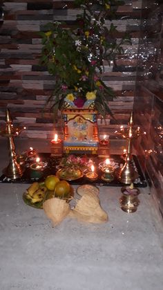 there are many fruits and candles on the table in front of this altar with flowers