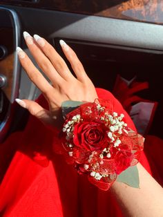 a woman's hand with white nails and red flowers on it, in the car