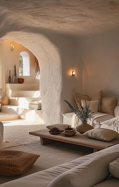 a living room filled with white furniture and pillows on top of couches in front of a stone wall