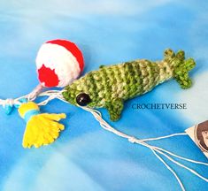 a crocheted green fish with a red and white ball on it's tail