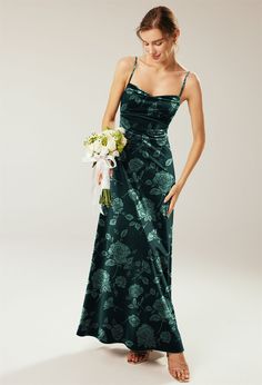 a woman in a long green dress holding a bouquet