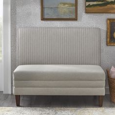 a couch sitting in front of a painting on the wall next to a basket filled with flowers