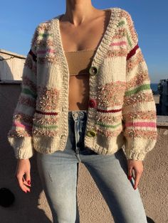 a woman standing on top of a roof with her hands in her pockets and wearing jeans