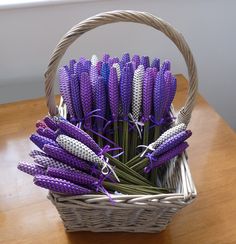 a wicker basket filled with purple and white decorative items on a wooden table next to a window