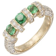 Emerald pave diamond wedding band ring. 3 round cut bright emeralds with 86 round accent diamonds in 18k yellow gold. 1 round bright green Emerald, approx. total weight .32cts, MI 2 round bright green Emeralds, approx. total weight .46cts, MI 86 round diamonds, approx. total weight .86cts, H, VS – SI Size 7 and sizable 18k yellow gold 8.3 grams Tested: 18k Stamped: 750 Width at top: 5.64mm Height at top: 5.37mm Width at Bottom: 3.48mm Emerald Diamond Ring With Pave Setting, Green Round Cut Jewelry With Pave Setting, Green Jewelry With Pave Setting Round Cut, Green Emerald Wedding Ring With Pave Setting, Green Pave Setting Wedding Ring, Green Diamond Ring With Pave Setting For Wedding, Green Diamond Half Eternity Ring, Green Pave Wedding Rings, Green Wedding Rings With Pave Setting