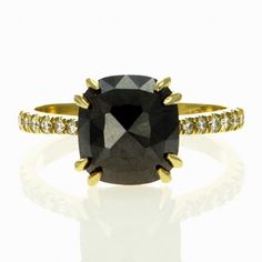 a black and white diamond ring with yellow gold accents on the band, set against a white background