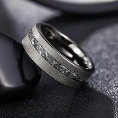 two wedding rings sitting on top of a black table next to a phone and remote control