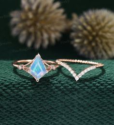 three different types of rings sitting on top of a green cloth with flowers in the background