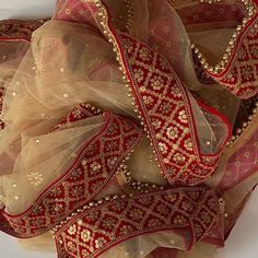 red and gold sari with golden thread work on the border, hanging from a white wall