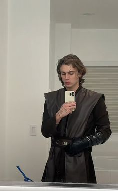 a man dressed in black taking a selfie with his cell phone