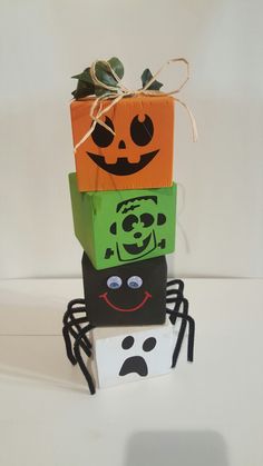 three halloween boxes stacked on top of each other with faces painted on them and one has a spider