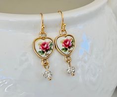 Sweet little heart dangle earrings Feature a lovely rose graphic. A tiny Crystal drop dangles below. They measure one and a quarter inches and hang from 18 karat gold plated ear wires. Your earrings will arrive packaged and ready for gifting. Vintage Heart Charm Drop Earrings, Vintage Drop Earrings For Valentine's Day, Vintage Heart Charm Earrings For Wedding, Elegant Heart Earrings With Dangling Charms As Gift, Vintage Charm Drop Earrings As Gift, Vintage Charm Drop Earrings For Gift, Delicate Dangling Charms Earrings, Vintage Rose Gold Dangle Earrings, Vintage Rose Gold Drop Earrings