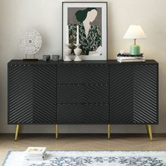 a black and gold sideboard sitting on top of a wooden floor next to a lamp