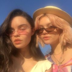 two young women standing next to each other in front of the sun wearing sunglasses and hats