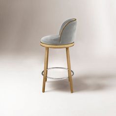 an upholstered bar stool with gold trimmings and a grey velvet seat