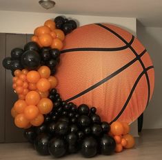 an orange and black basketball surrounded by balloons in the shape of a ball on a wall