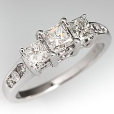 a three stone diamond ring with diamonds on the band and sidestones set in 18k white gold