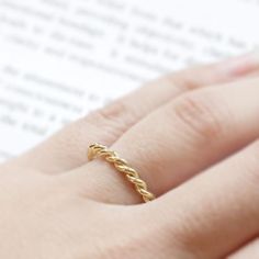 a woman's hand with a ring on top of her finger and an open book in the background