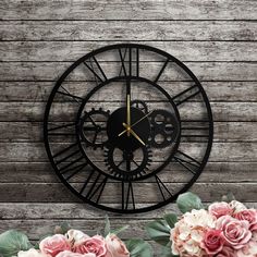 a black clock with gears and flowers on a wooden wall next to some wood planks