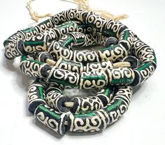 About this item  African glass beads for handmade jewelry and other arts and crafts. Available Colors: Brown & Cream with Green Stripe, Black & Cream with Green Stripe, Red & Cream with Green Stripe, Teal & Cream with Red Stripe, Bead Size: Approximately: 12mm by 17mm to 18mmNumber of Beads on a strand: 15 Size of Hole: 2.0mm - 3mm All our African beads are handmade as such there are  variations in the color, shapes, and sizes even on the same strand or band. You may not get the exact same bead in terms of color, shape, or size on listings. It is normal to finds earthen particles on a bead. It is normal to find uneven edges or even chipped edges. Even though our beads are durable, they are mostly made from glass and must be handle with care Unique Green Beads For Crafting, Green Hand-strung Beads For Crafting, Unique Green Wooden Beads, Artisan Spacer Beads For Crafting, Artisan Black Beads For Crafting, Handmade Green Beads For Crafting, Vintage Green Wooden Beads, Clay Supplies, Pave Beads