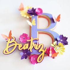 the letter b is decorated with flowers and butterflies on it's letters are purple, red, yellow, and pink