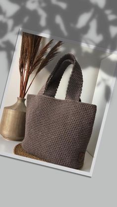 a knitted bag sitting on top of a table next to a vase with a plant in it