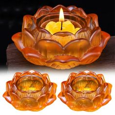 an orange glass candle holder with two candles in the center and three petals on each side