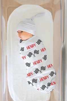 a baby wrapped in a white sheet with black and red words