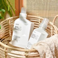 two bottles of shampoo sitting on top of a wicker basket next to a potted plant