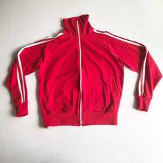 "1970s red warm up track jacket has white stripes down the sleeves, and a white front zipper. The jacket has welt hip pockets, knit rib at the sleeve cuffs and hem, and has a collar that can be worn zipped up or down. Label is Andia, 100% stretch nylon, made in Taiwan. Condition Excellent. Measurements Chest 48\" Waist 46\" Sleeve length 31\" (from neck, raglan) Length 24\" Tag size is large." Indigo Floral, Mens Hoodies, Muscle Shirts, Western Shirts, Blue Suede, Track Jacket, Track Jackets, Front Zipper, Adidas Jacket