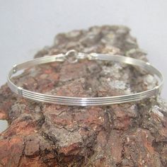 A simple design--four plain square sterling silver wires for a bangle-style look. Pure, uncluttered lines, and stackable with most of my other wirewrapped bracelets! An excellent choice for a graduation, birthday, or holiday gift for that favorite lady in your life. The built-in hook and eye-type clasp is easy to get on and off. Choose the size you want from the variations listed, and get a perfect, comfortable fit. Classic Bangle Bracelets For Friendship, Classic Friendship Bangle Bracelets, Adjustable Sterling Silver Bangle For Everyday, Adjustable Everyday Sterling Silver Bangle Bracelet, Adjustable Bangle Bracelet With Simple Design, Everyday Hand Wrapped Bangle Bracelet, Classic Band Bracelets As A Gift, Classic Band Bracelets As Gifts, Classic Band Bracelets For Gifts