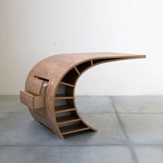 a curved wooden table sitting on top of a tiled floor