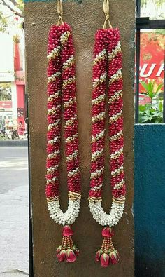 pair of red and white beaded earrings hanging from hooks on the side of a building