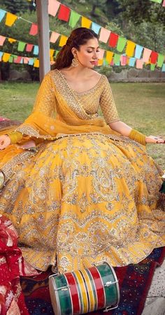 a woman sitting on top of a colorful rug wearing a yellow and gold dress with matching accessories