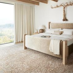 a bedroom with a large bed and wooden beams on the ceiling, along with an open window